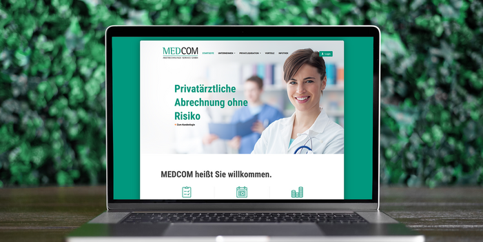 Laptop auf Holztisch mit Screenshot der Medcom-Website